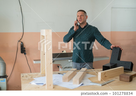 Portrait of a Caucasian man talking on the phone in a workshop. 101278834