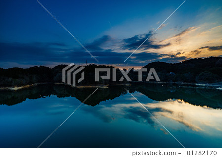 長時間曝光（山腰上的太陽落山）下流動的雲層和鏡面般的水面② 2023 年春季奈良布米水壩 101282170