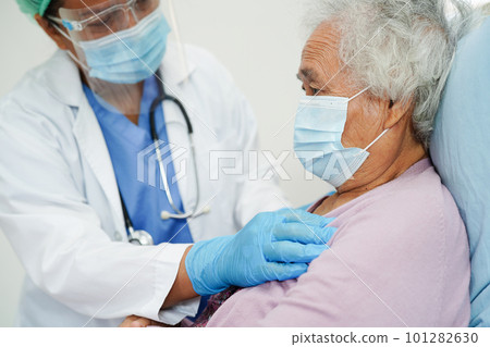 Doctor in ppe user infrared thermometer to check temperature of asian elderly woman patient for safety to protect covid 19 virus. 101282630