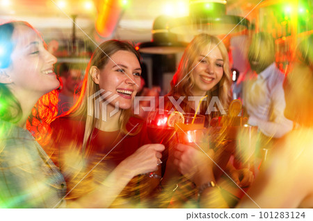 Chatting friends holding cocktails and laughing in nightclub 101283124