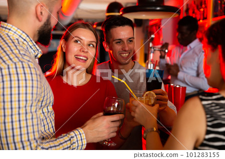 Portrait of happy young woman with colleagues enjoying corporate party in bar 101283155