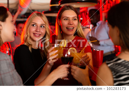 Female friends enjoying wine in night club 101283173