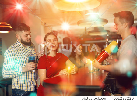 Young man bartender shaking cocktail for friends during patry Young man bartender shaking cocktail for friends during patry 101283229