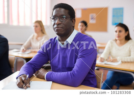 Adult african american man in glasses listening to lecture in classroom Adult african american man in glasses listening to lecture in classroom 101283308