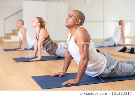 Nice people exercising during yoga class in fitness center Nice people exercising during yoga class in fitness center 101283314