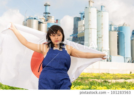 Worried asian girl in work clothes with flag of japan standing in front of industrial scenery Worried asian girl in work clothes with flag of japan standing in front of industrial scenery 101283563