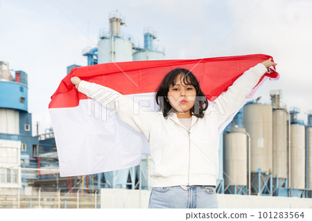 Worried asian girl with flag of indonesia standing in front of industrial scenery Worried asian girl with flag of indonesia standing in front of industrial scenery 101283564