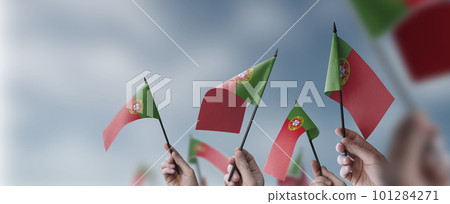 A group of people holding small flags of the Portugal in their hands A group of people holding small flags of the Portugal in their hands 101284271