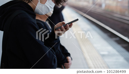 一個年輕人在站台等火車時看手機 一個年輕人在站台等火車時看手機 101286499
