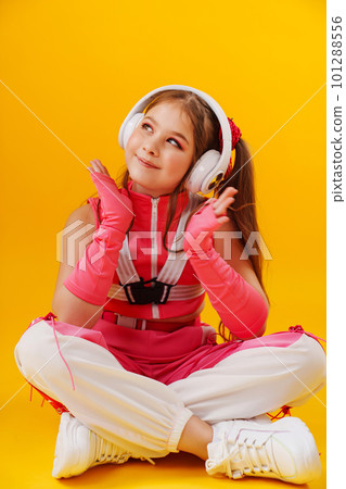 a teenage girl in a pink stage costume and headphones on a yellow background. a teenage girl in a pink stage costume and headphones on a yellow background. 101288556