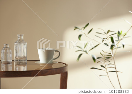 This room has a calm atmosphere with natural light. There are clay pots, glass bottles, coffee and various objects on the table. 101288583