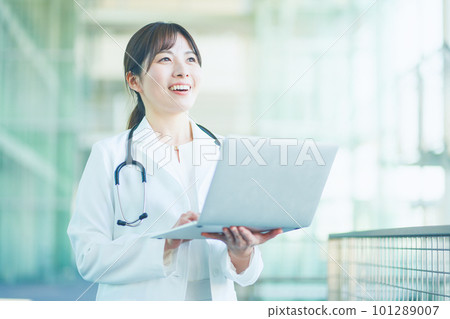 A female doctor in a white coat with a personal computer 101289007