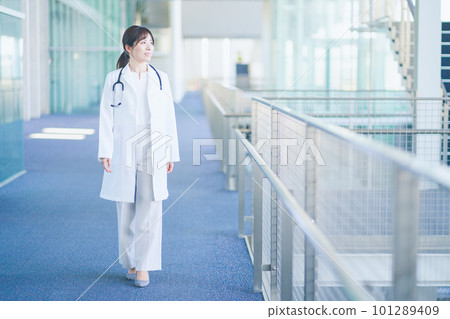 A female doctor wearing a white coat walking in the hospital 101289409