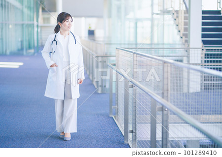 A female doctor wearing a white coat walking in the hospital 101289410