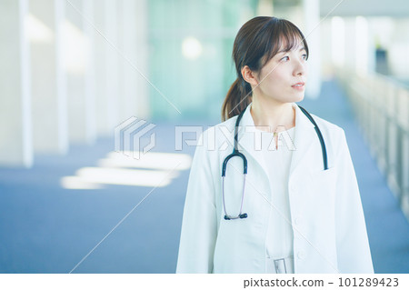 A female doctor wearing a white coat walking in the hospital A female doctor wearing a white coat walking in the hospital 101289423