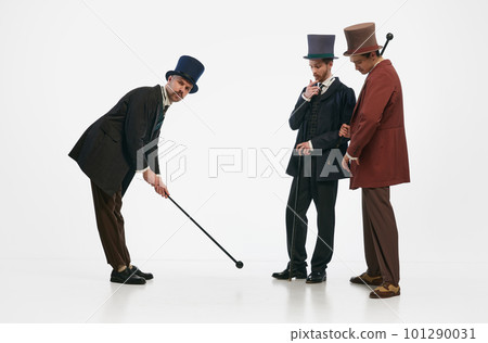 Portrait with three men wearing old-fashioned clothes and cylinder hats having fun ogether over white background. Entertain 101290031