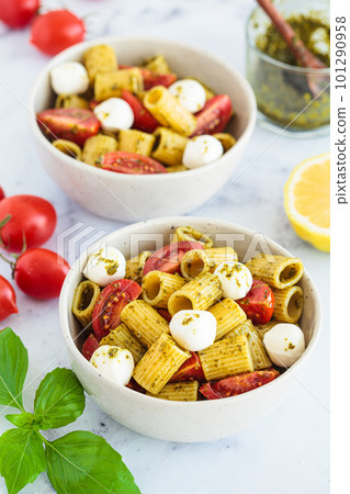 Rigatoni pasta with pesto, tomatoes and mozzarella in white bowl. Italian cuisine concept. 101290958