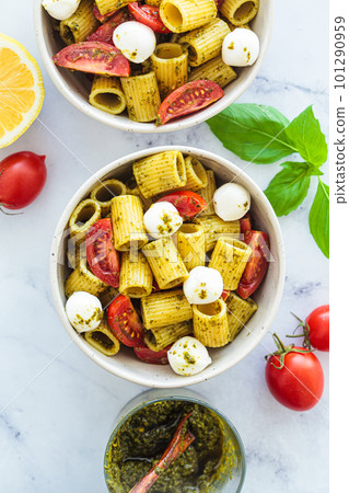 Rigatoni pasta with pesto, tomatoes and mozzarella in white bowl. Italian cuisine concept. 101290959
