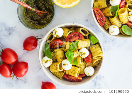 Rigatoni pasta with pesto, tomatoes and mozzarella in white bowl. Italian cuisine concept. 101290960