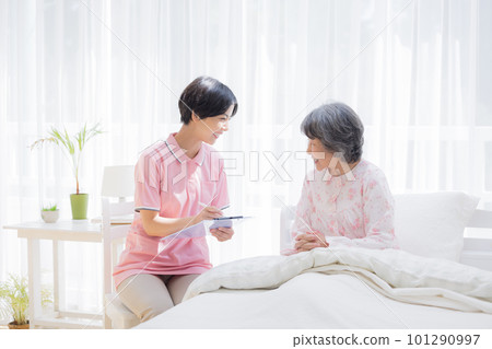 家訪護理員採訪坐在床上的老年婦女 101290997