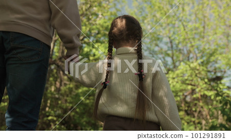 father leads child by hand outdoors. happy family park. dad daughter go walk holding hands. chidhood dream. kid with dad picnic. little child weekend nature with man father. teamwork. joint vacation 101291891