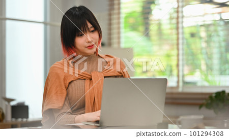 Portrait of young stylish woman using laptop at home office. Freelance, creative occupation, e-learning concept Portrait of young stylish woman using laptop at home office. Freelance, creative occupation, e-learning concept 101294308