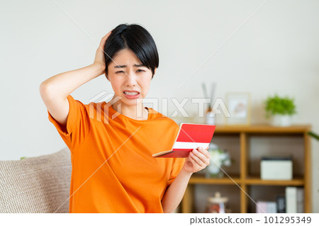 A worried young woman looking at a passbook in the living room A worried young woman looking at a passbook in the living room 101295349