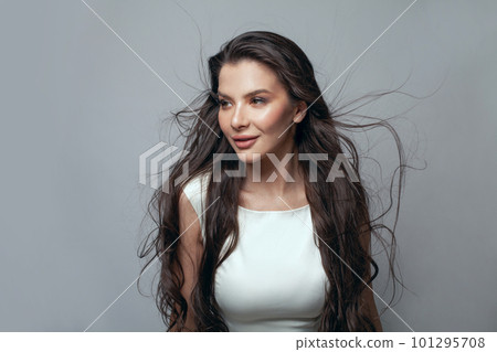 Cute nice woman fashion model with makeup and long black hair in the studio on a gray background 101295708