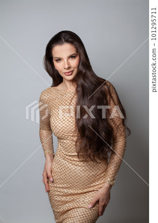 Fashionable lady woman wearing golden evening gown against gray studio wall background 101295711