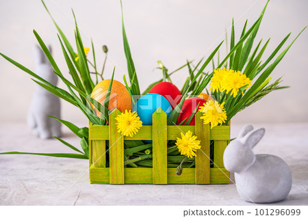 Easter spring decoration with painted eggs, rabbits, field flowers, wooden box and wheatgrass 101296099
