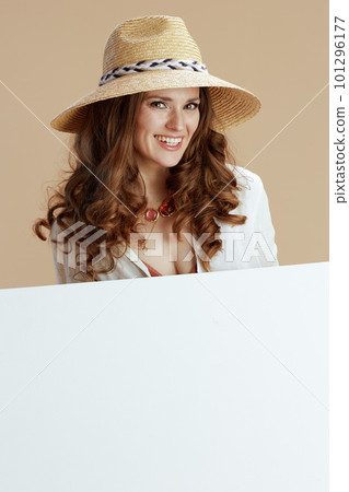 smiling trendy woman showing blank board on beige 101296177