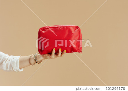 Modern woman in blouse and shorts with firstaid kit on beige 101296178