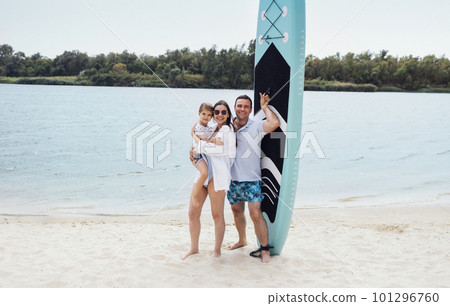 Joyful married couple of surfers with their cute daughter on the beach. Joyful married couple of surfers with their cute daughter on the beach. 101296760