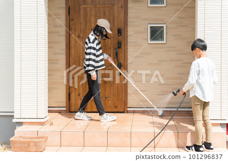 Elementary school boys and girls cleaning the dirt floor of the entrance with a brush 101296837