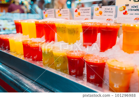 Colorful tropical fruit smoothie, fresh cold drinks with ice, on street market shop stall. Selected focus. Healthy fast food concept. 101296988