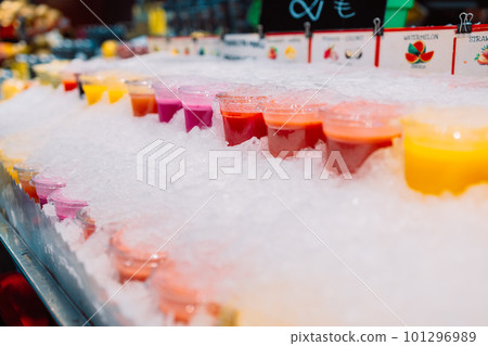 Colorful tropical fruit smoothie, fresh cold drinks with ice, on street market shop stall. Selected focus. Healthy fast food concept. 101296989