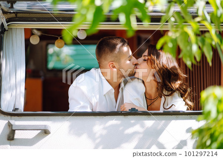 Beautiful wedding couple laugh and kiss relaxing in rv, camping in a trailer. Romantic moment. 101297214