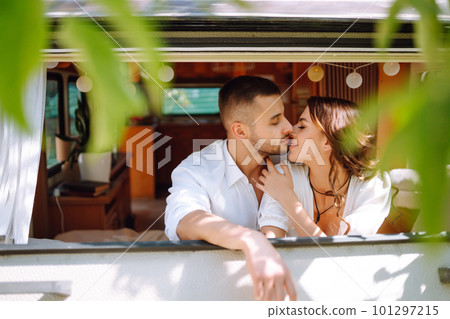 Beautiful wedding couple laugh and kiss relaxing in rv, camping in a trailer. Romantic moment. 101297215