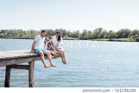 Happy family on wooden bridge against the backdrop of the sea or lake. Happy family on wooden bridge against the backdrop of the sea or lake. 101298280