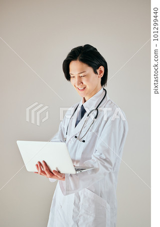 A young man in a white coat operating a personal computer A young man in a white coat operating a personal computer 101299440