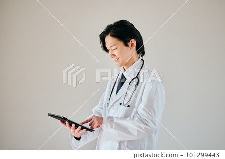A young man in a white coat operating a tablet A young man in a white coat operating a tablet 101299443