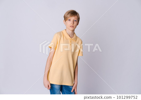 Cute emotional teenager boy in yellow t-shirt posing in studio on light Cute emotional teenager boy in yellow t-shirt posing in studio on light 101299752