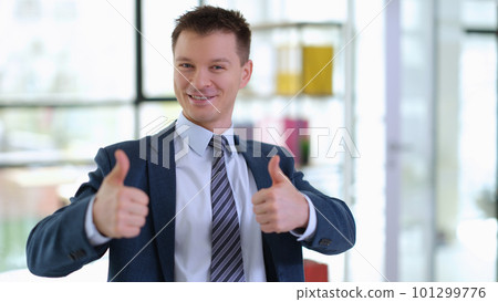 Successful businessman in suit showing thumbs up in office 101299776