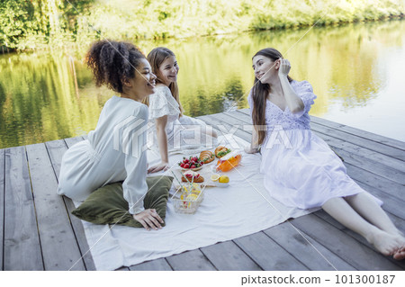 Happy female friends on picnic on the bank of a river Happy female friends on picnic on the bank of a river 101300187