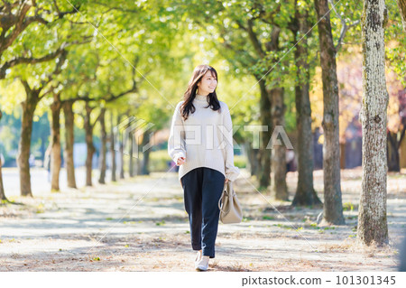 走在綠樹成蔭的街道上的年輕女人 101301345