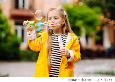 Cute little girl in the autumn on a walk blowing soap bubbles. Childhood, active rest, lifestyle concept. Cute little girl in the autumn on a walk blowing soap bubbles. Childhood, active rest, lifestyle concept. 101301733