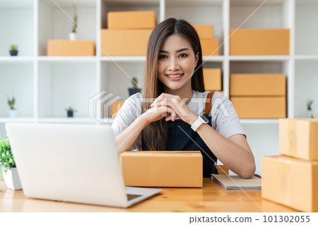 Young pretty asian start up business woman in apron working with online parcel box warehouse selling online product Young pretty asian start up business woman in apron working with online parcel box warehouse selling online product 101302055
