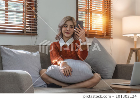 Young woman on video call, relaxing and surfing through internet with cellphone Young woman on video call, relaxing and surfing through internet with cellphone 101302124