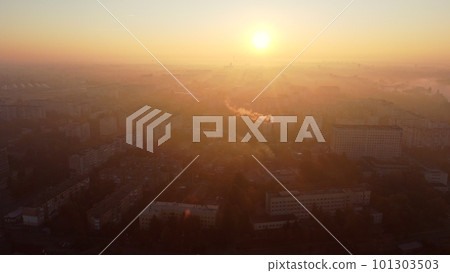 Beautiful cityscape in summer at sunrise. Flying over many multi-storey buildings and a chimney with white smoke. Bright shining sun. Urban landscape. Dawn sunrise dawning sunset sundown, rising sun. Beautiful cityscape in summer at sunrise. Flying over many multi-storey buildings and a chimney with white smoke. Bright shining sun. Urban landscape. Dawn sunrise dawning sunset sundown, rising sun. 101303503