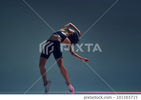Sportive young woman with relief, slim, fit body in sportswear training against grey studio background 101303715